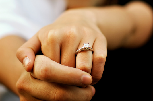 man and woman holding hands and the woman is wearing a diamond engagement ring