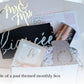 An open white fiance themed gift box containing a fiancee tshirt, a insulated bride themed wine tumbler, and "i do" ring dish, a gold bracelet, a diamond topped pen, wedding planning notepad, and a cake topper